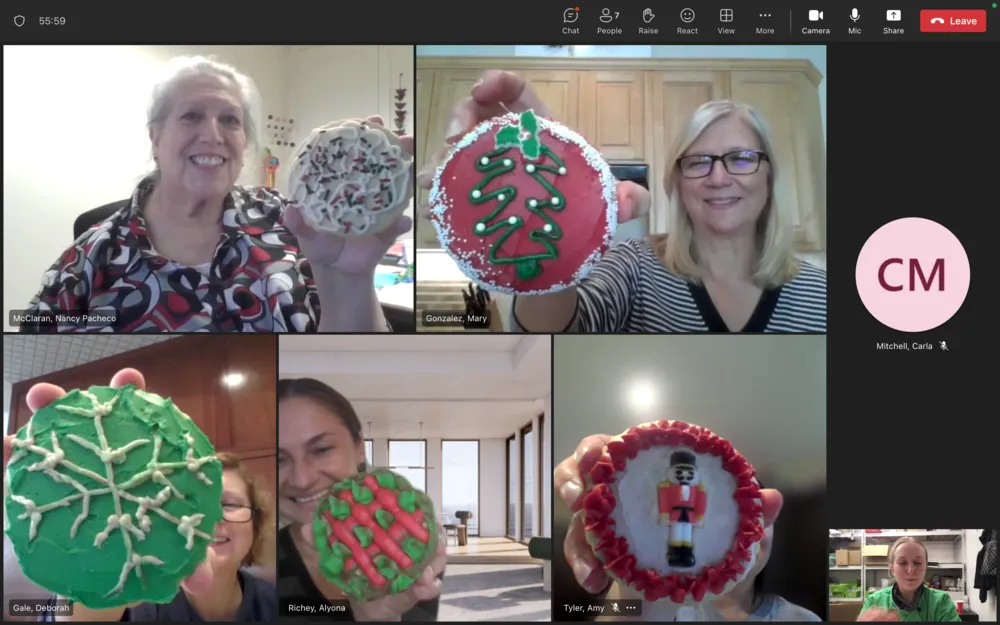 Employees holding decorated Christmas cookies